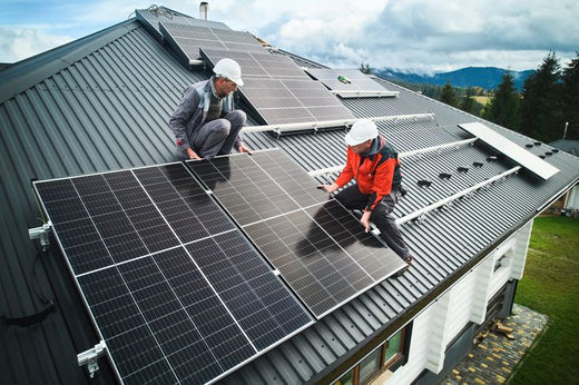 Zwei Arbeiter installieren Solarpanels auf einem Dach.