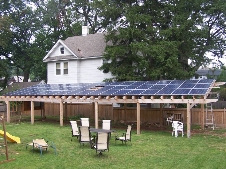 Solar panels installed on a wooden pergola in a backyard.